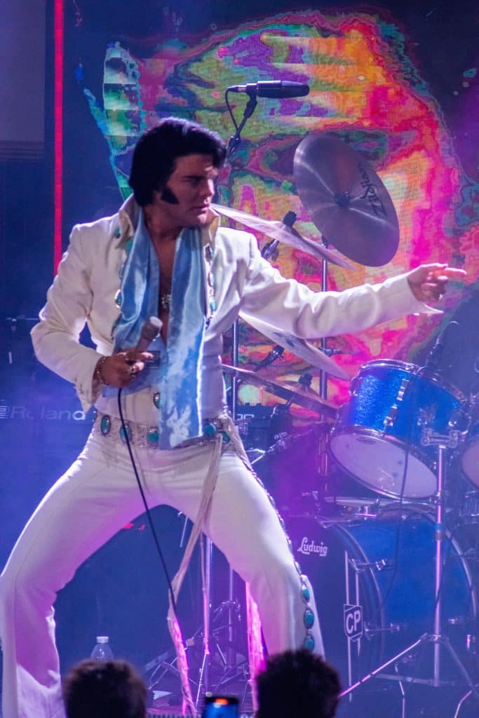 Elvis impersonator JD King on stage in white jumpsuit
