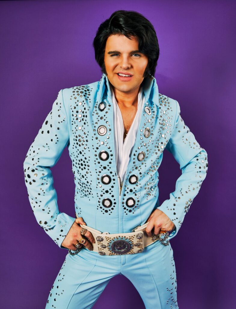 Elvis impersonator JD King in a blue jumpsuit with purple background